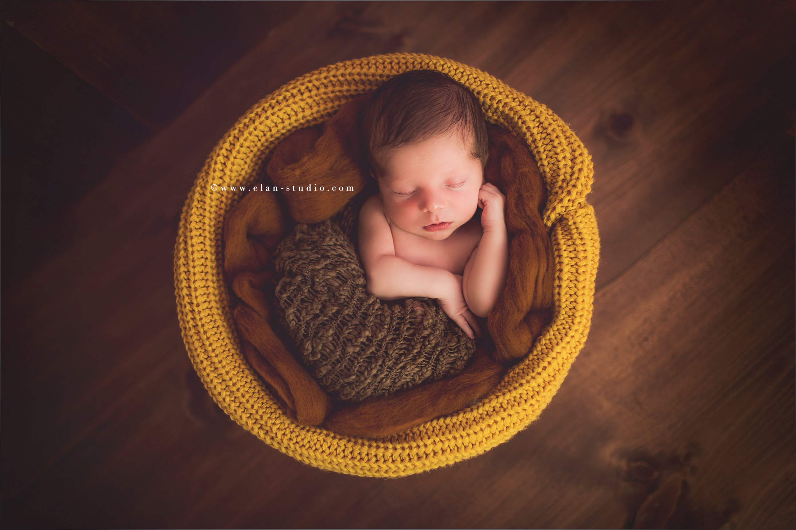 newborn baby wrapped in brown and mustard