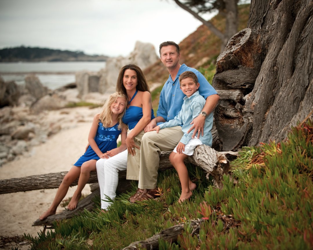 Smiling family on tree stump at Carmel beach