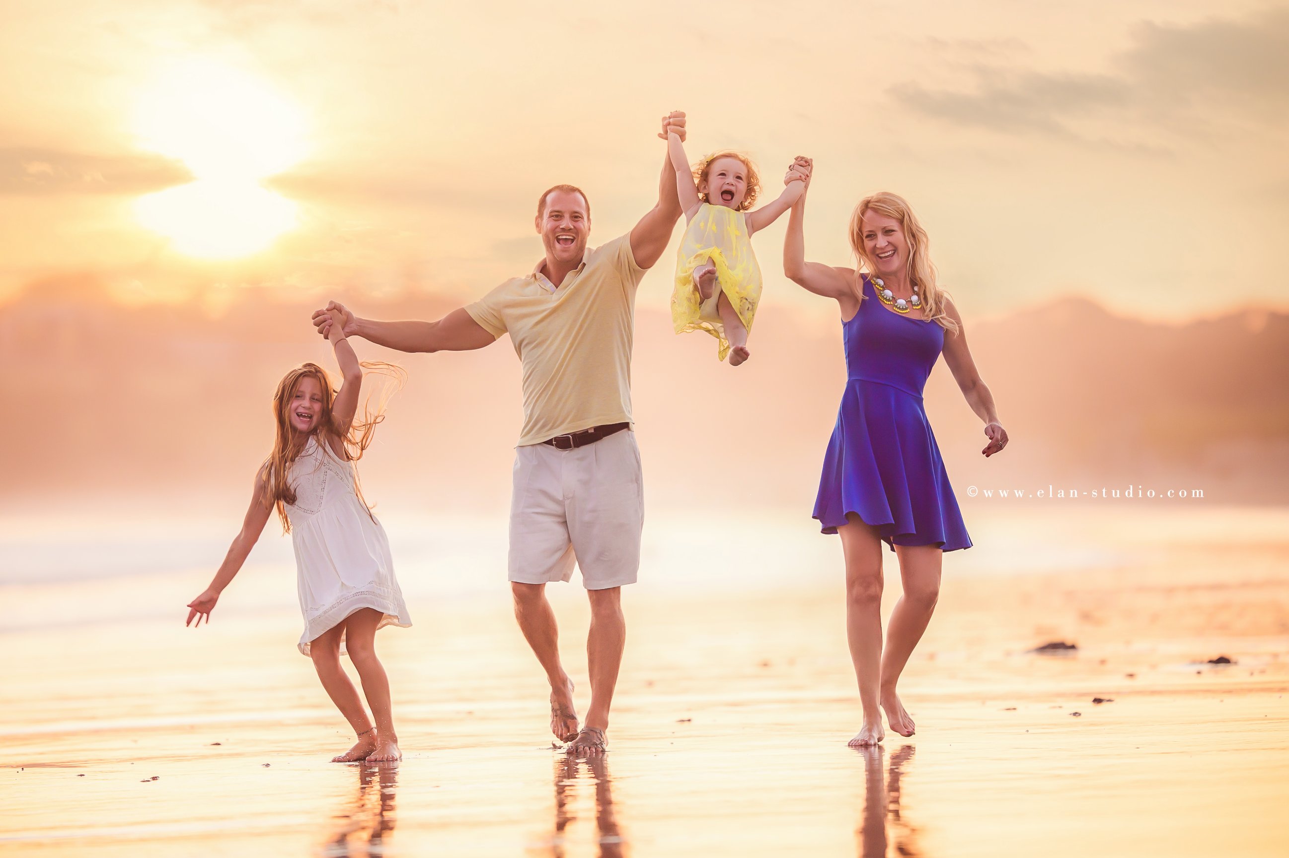 fit family with two girls walking along beach