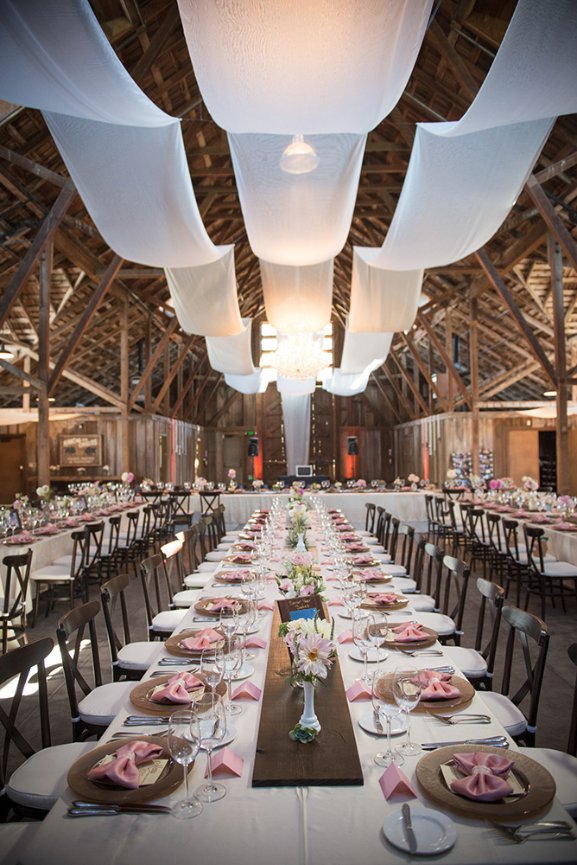 Barn wedding table arrangements and ceiling drapes