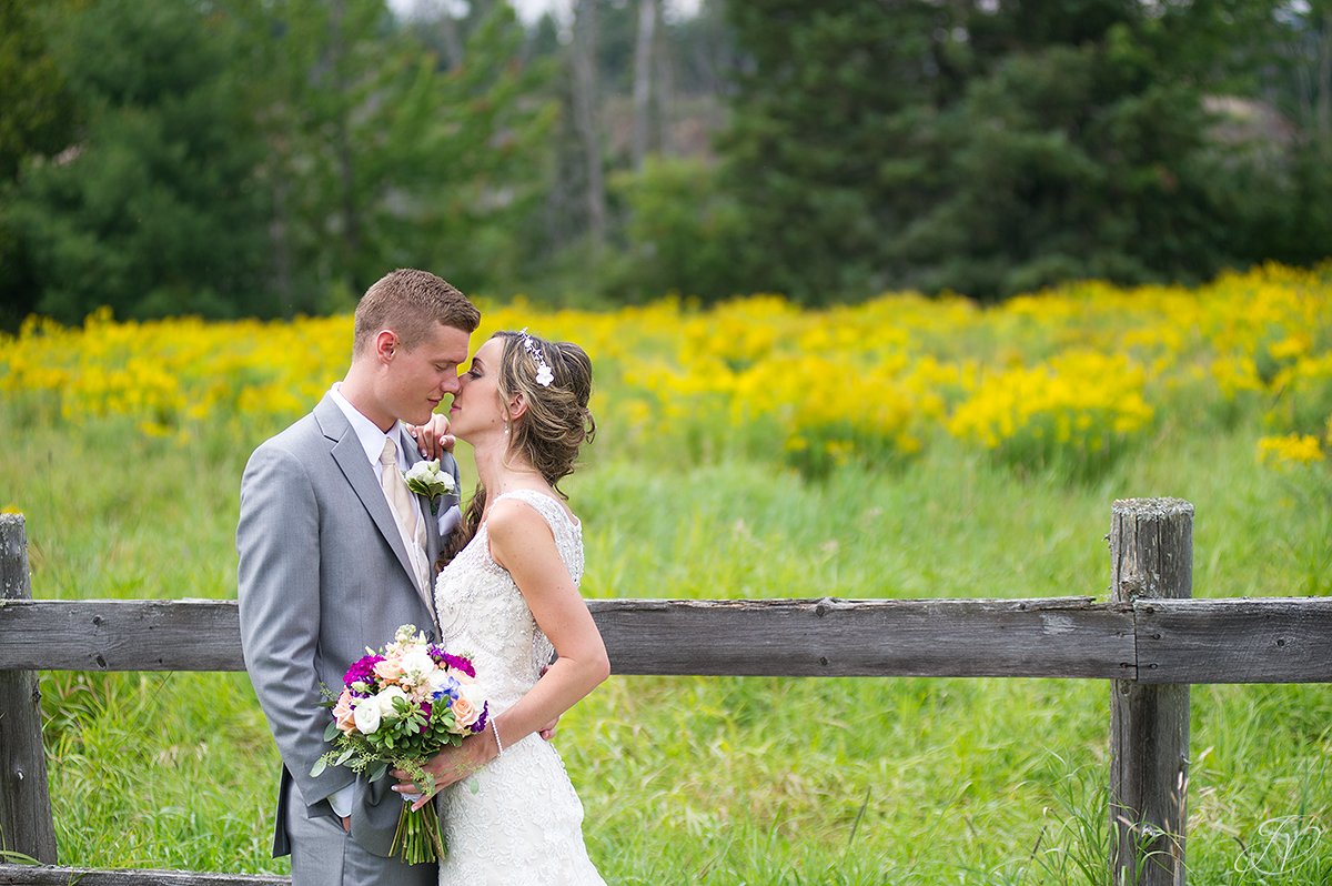 bride and groom near fence lake placid yellow flowers