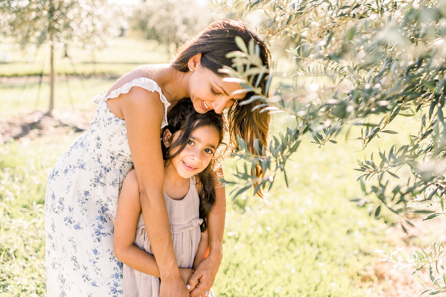 mother embracing daughter, girl looking at camera, olive tree, Florida, Ryaphotos