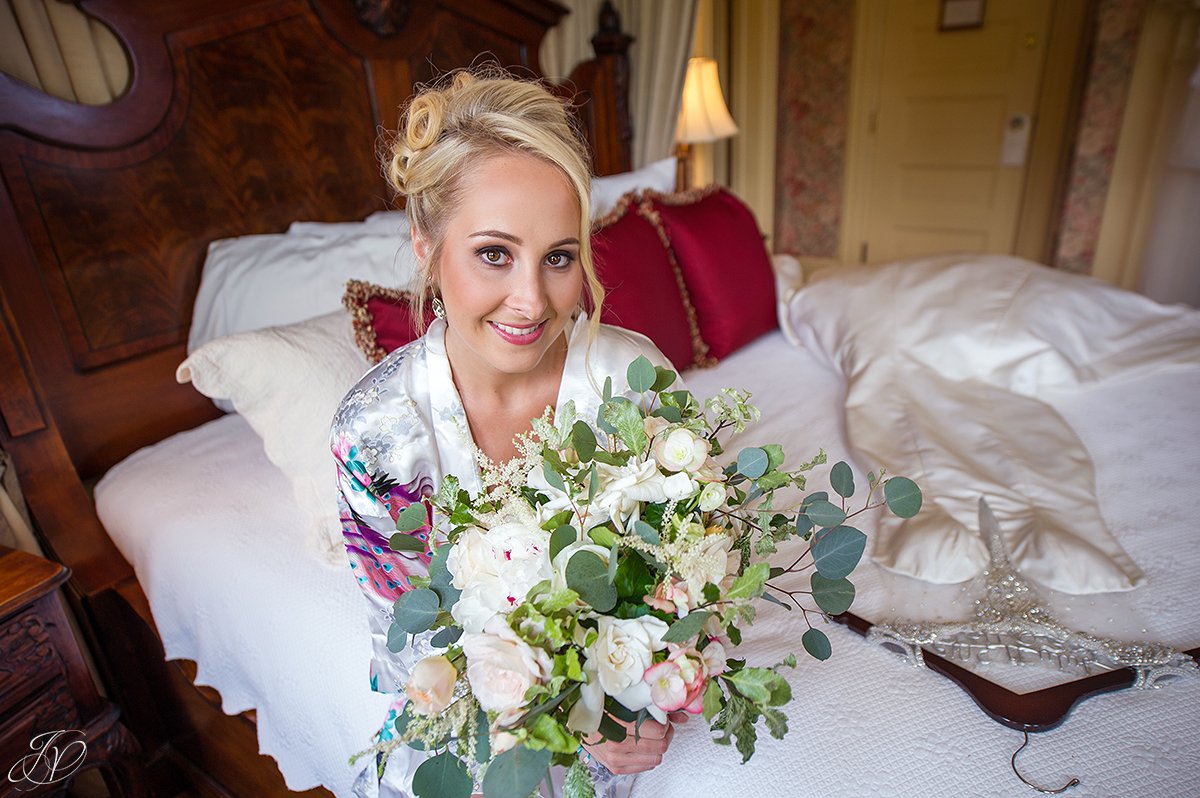 bride in getting ready robe with bouquet at inn at erlowest