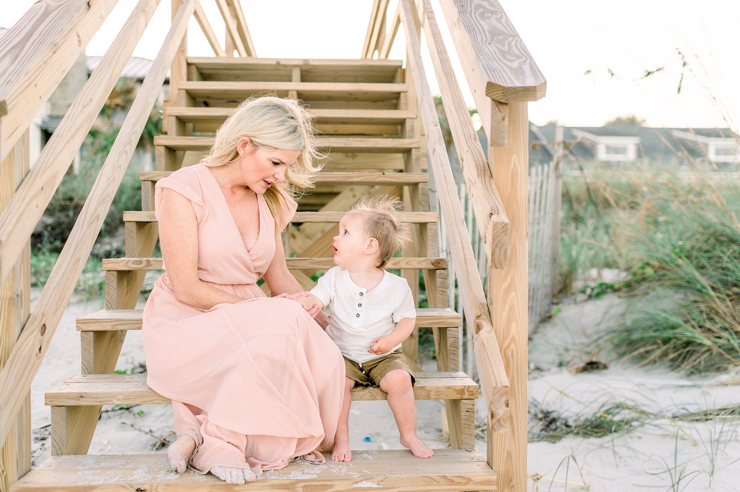 mommy and son sitting on wooden beach stairs, sandy feet, beach homes in background, Rya Duncklee