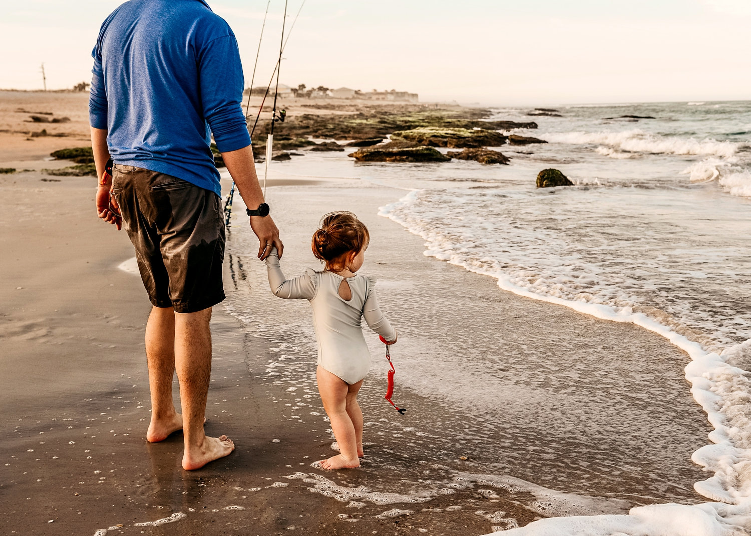 two year old girl holding orange fishing lure, daddy and daughter fishing