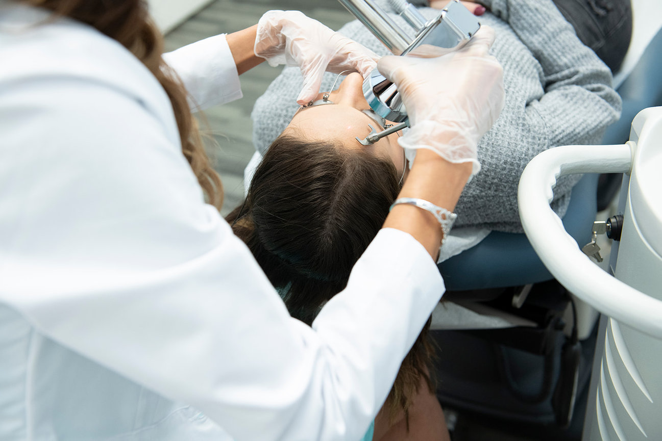 Patient receiving a skincare treatment as an aesthetician  uses tools while wearing gloves.
