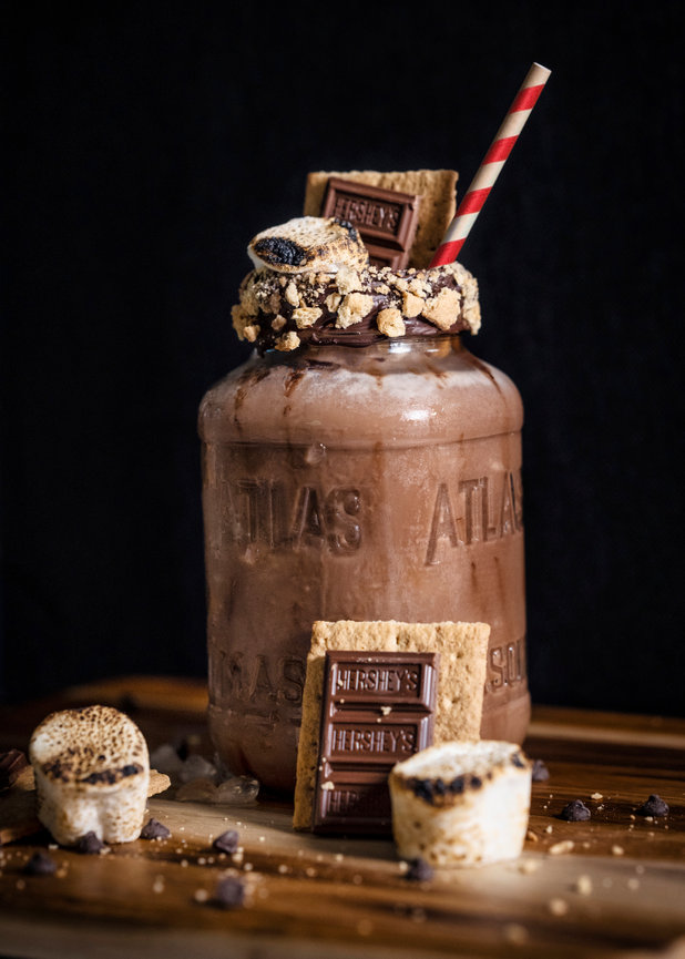 Chocolate milkshake in a mason jar, topped with graham crackers, chocolate bars, and toasted marshmallows.