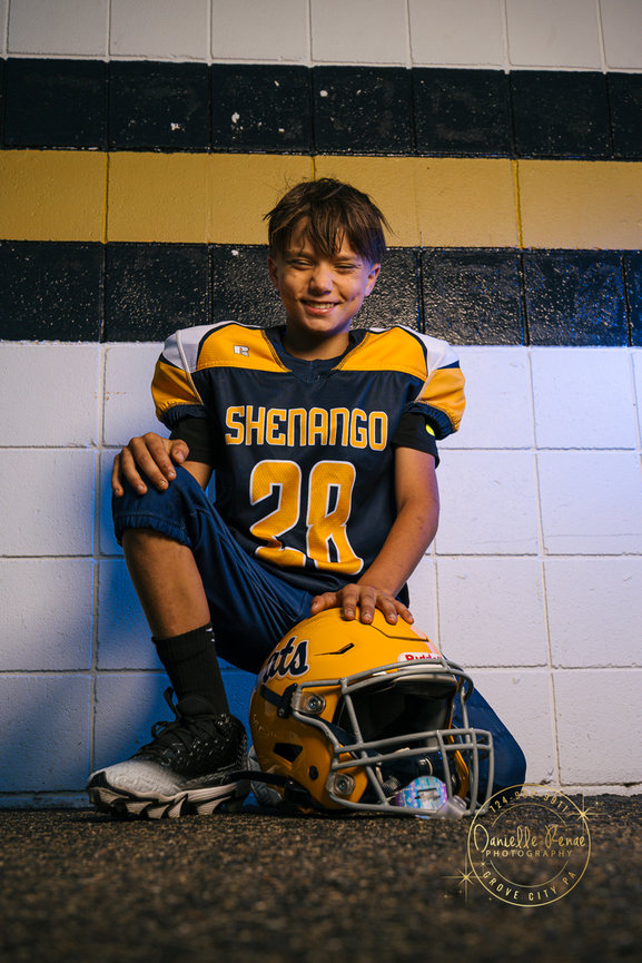 youth football player kneeling with his hand on his helmet