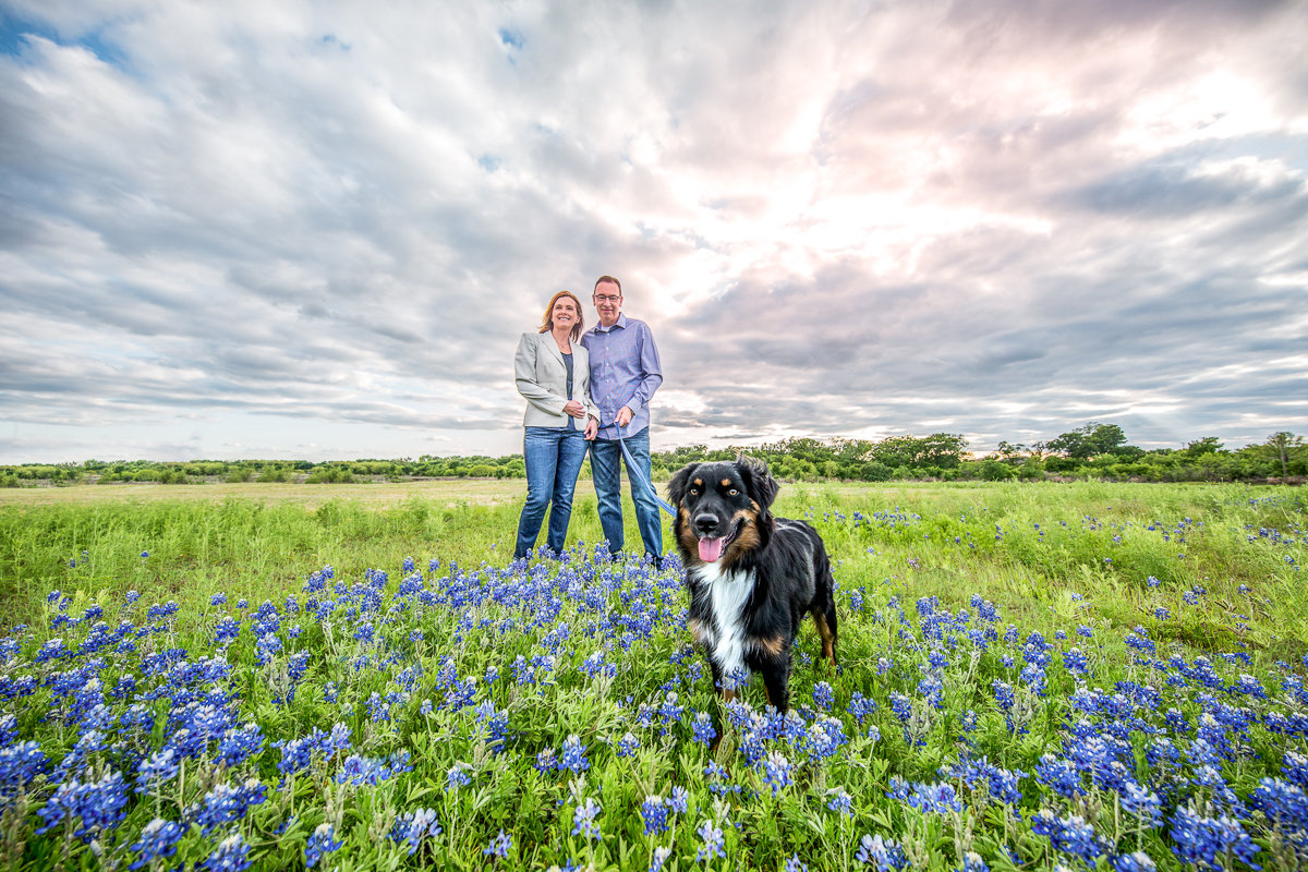 Family standing with a dog in a field of blue flowers