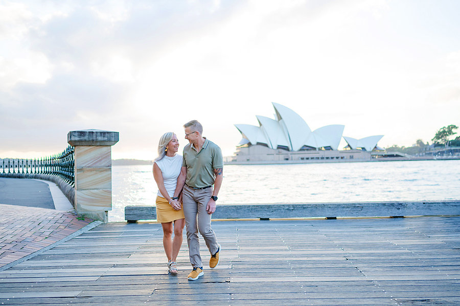 Couple walking embracing in front of the Sydney Opera House