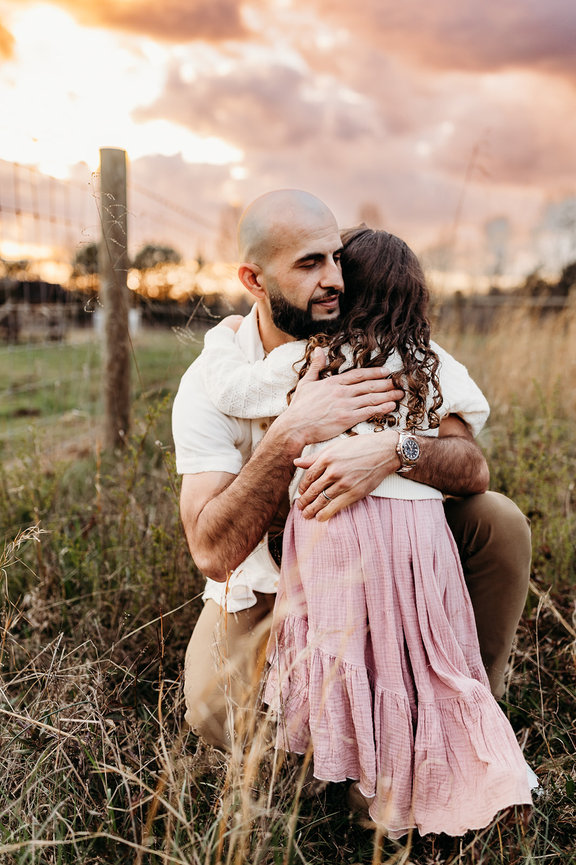 a father embraces his young daughter in a sunlit field in a Huntsville, Alabama photoshoot
