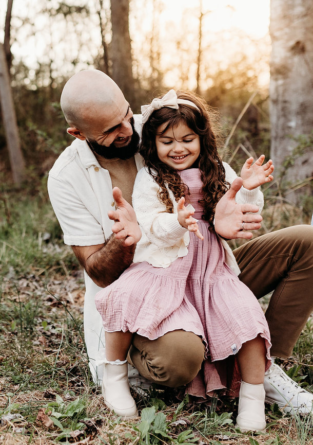 a father holds his daughter on his knee as they play a clapping game in a Huntsville, Alabama family photoshoot