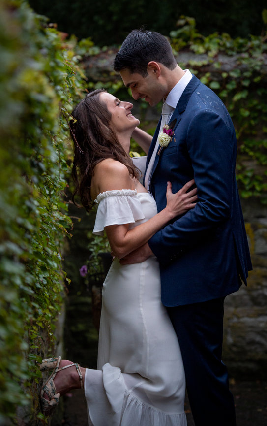 Beautiful curly brown-haired bride in a white dress poses for a photographer,  standing under a veil in a beautiful dress with sleeves. Wedding photography,  close-up portrait, chic hairstyle. 36426346 Stock Photo at