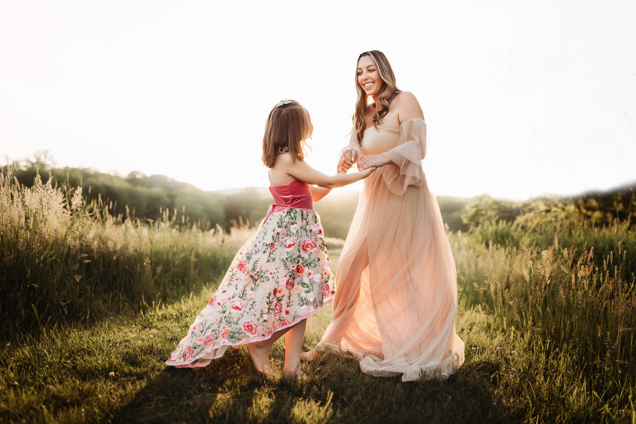 A mother and daughter dancing in a field during sunset at the Central Park of Morris County.