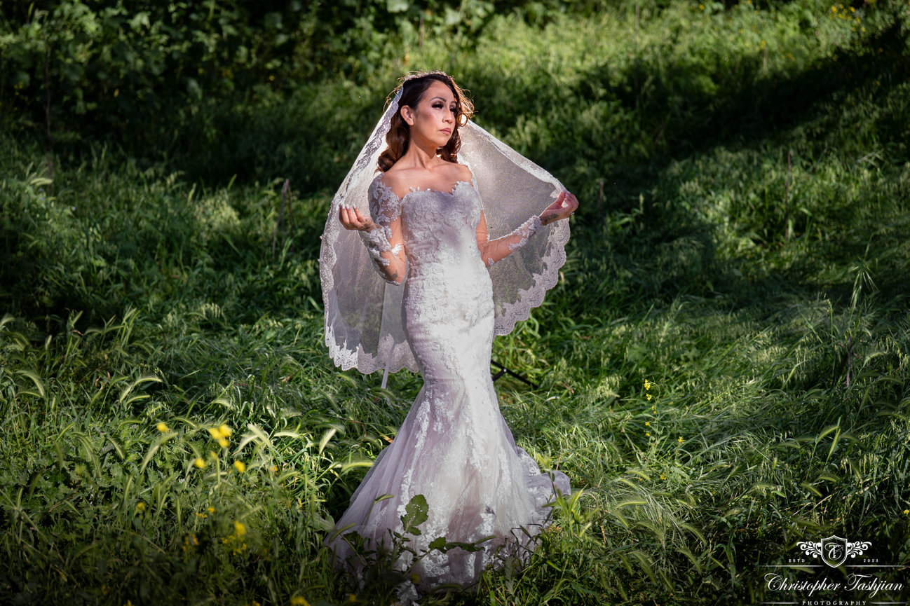 Bride holding veil in lush greenery