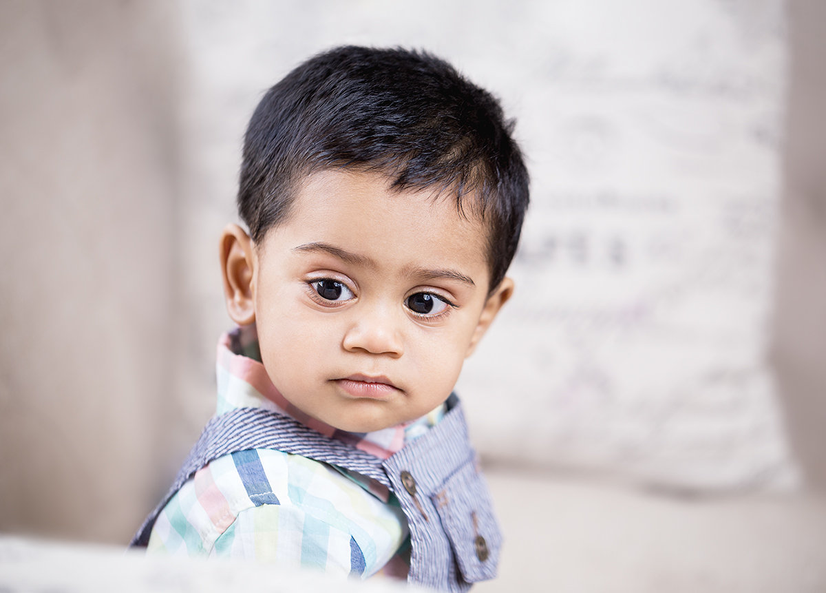 Indoor portrait of a young child with a soft, thoughtful expression, captured in natural-style light with a calm and emotive fine art feel