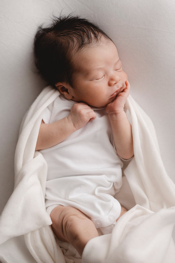 Sleeping newborn baby swaddled in white on a soft blanket