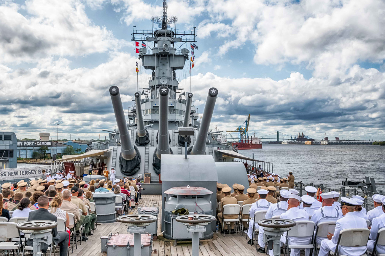 A crowd of naval officers and enlisted on a Battleship for a retirement ceremony
