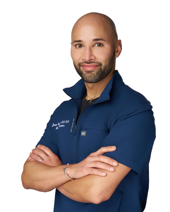 Professional headshot of a male medical professional wearing blue scrubs against a white background, photographed in Sherman Texas for healthcare branding
