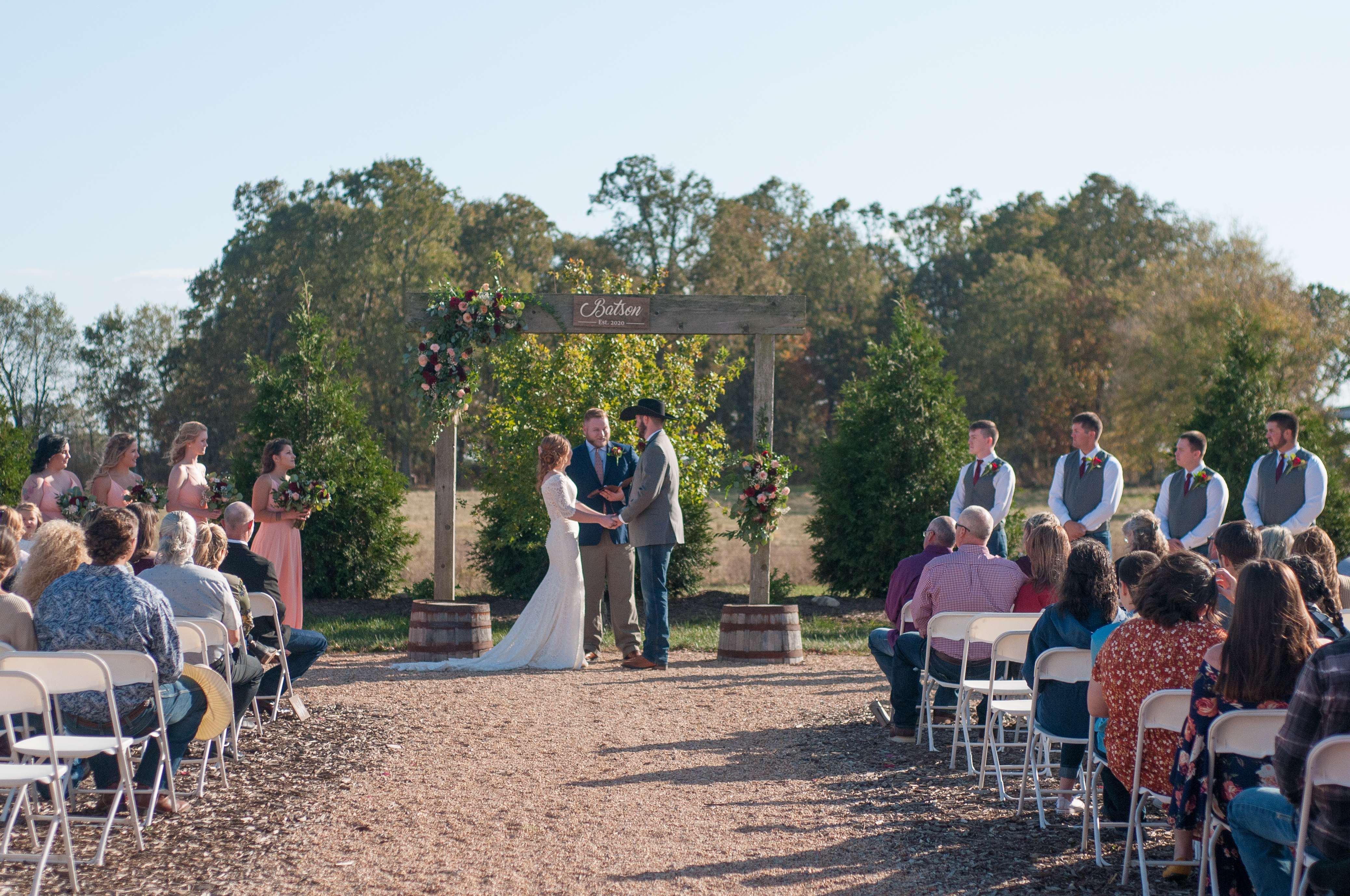 Bride and groom holding hands during the wedding ceremony with wedding aisle in foreground.