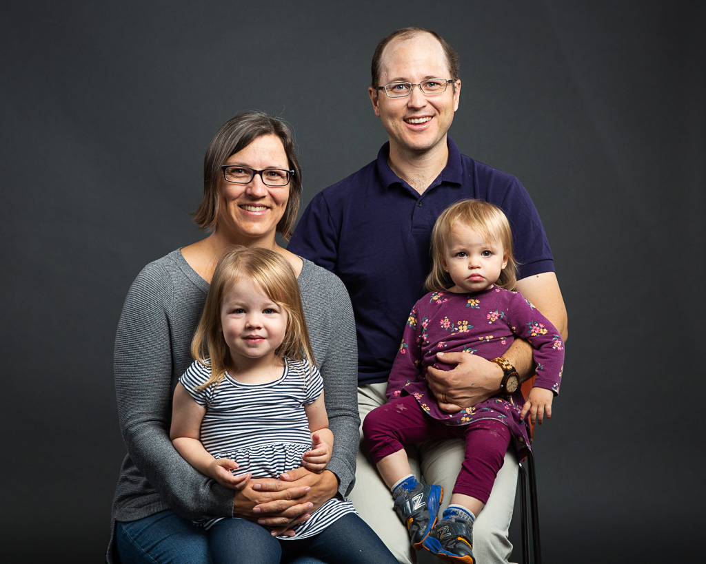 A formal in-studio family portrait of four with two parents and two children