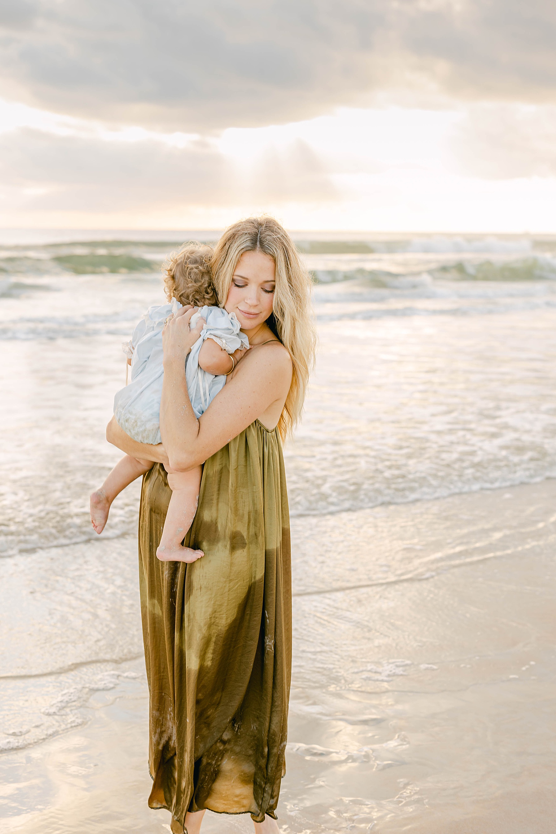 woman in green dress holding baby on the beach in st. augustine florida