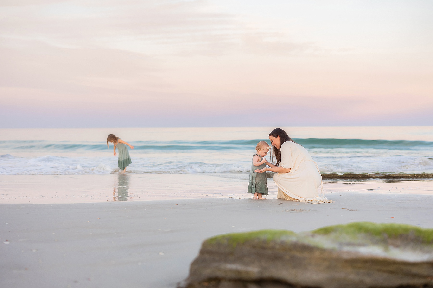 pastel skies at the beach in st. augustine florida with woman playing in the water with her two kids