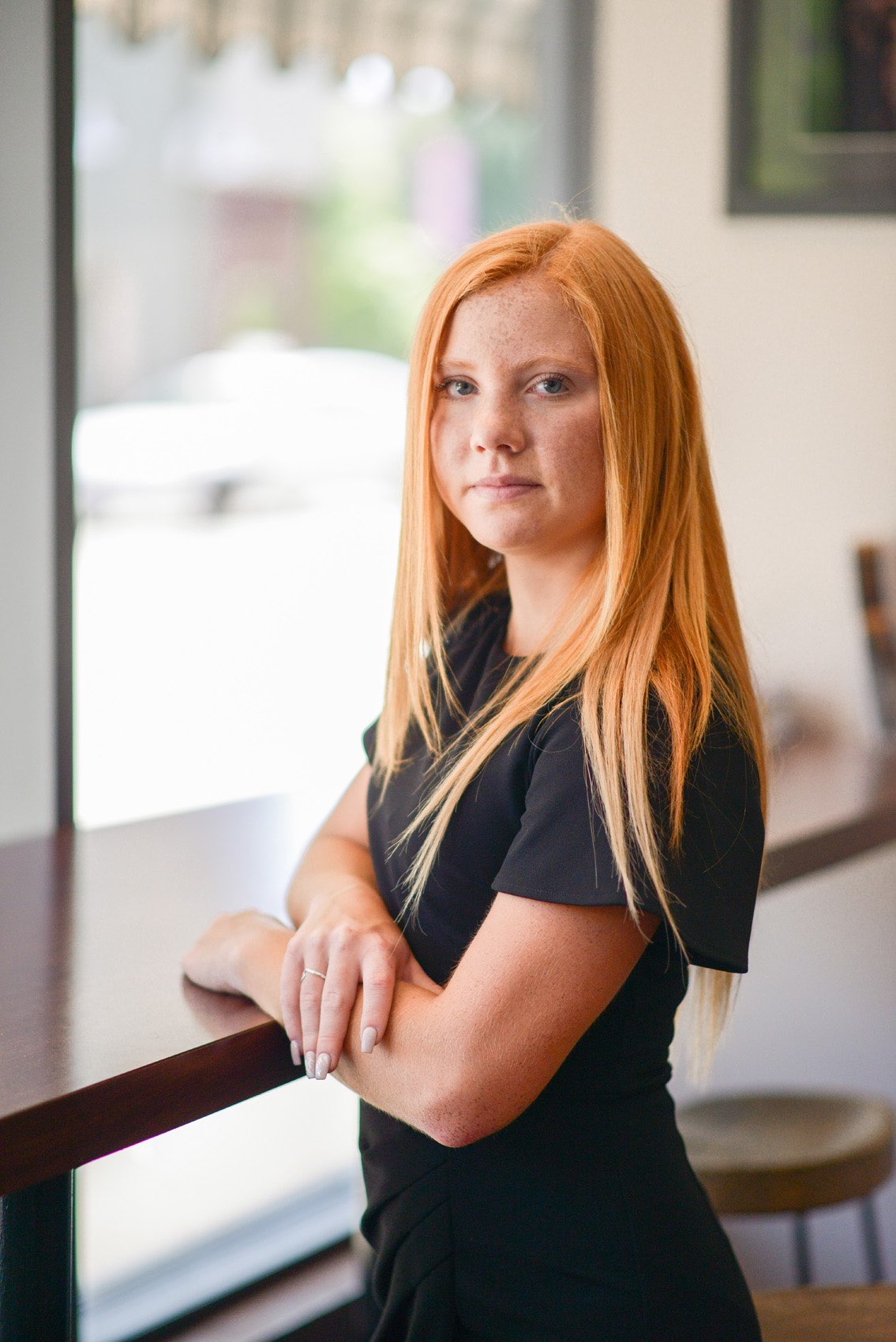 Senior girl in black dress at a counter in the European Cafe in Springfield, Missouri.