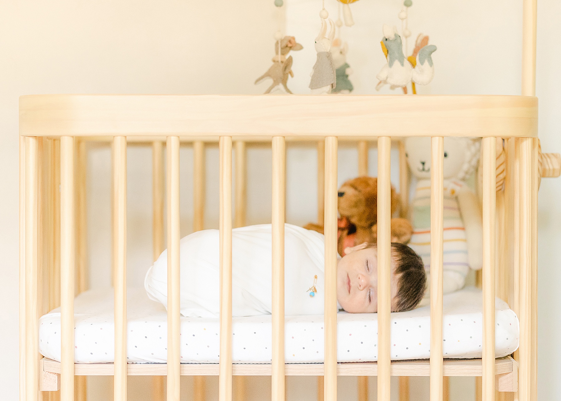 newborn baby boy sleeping in his neutral crib