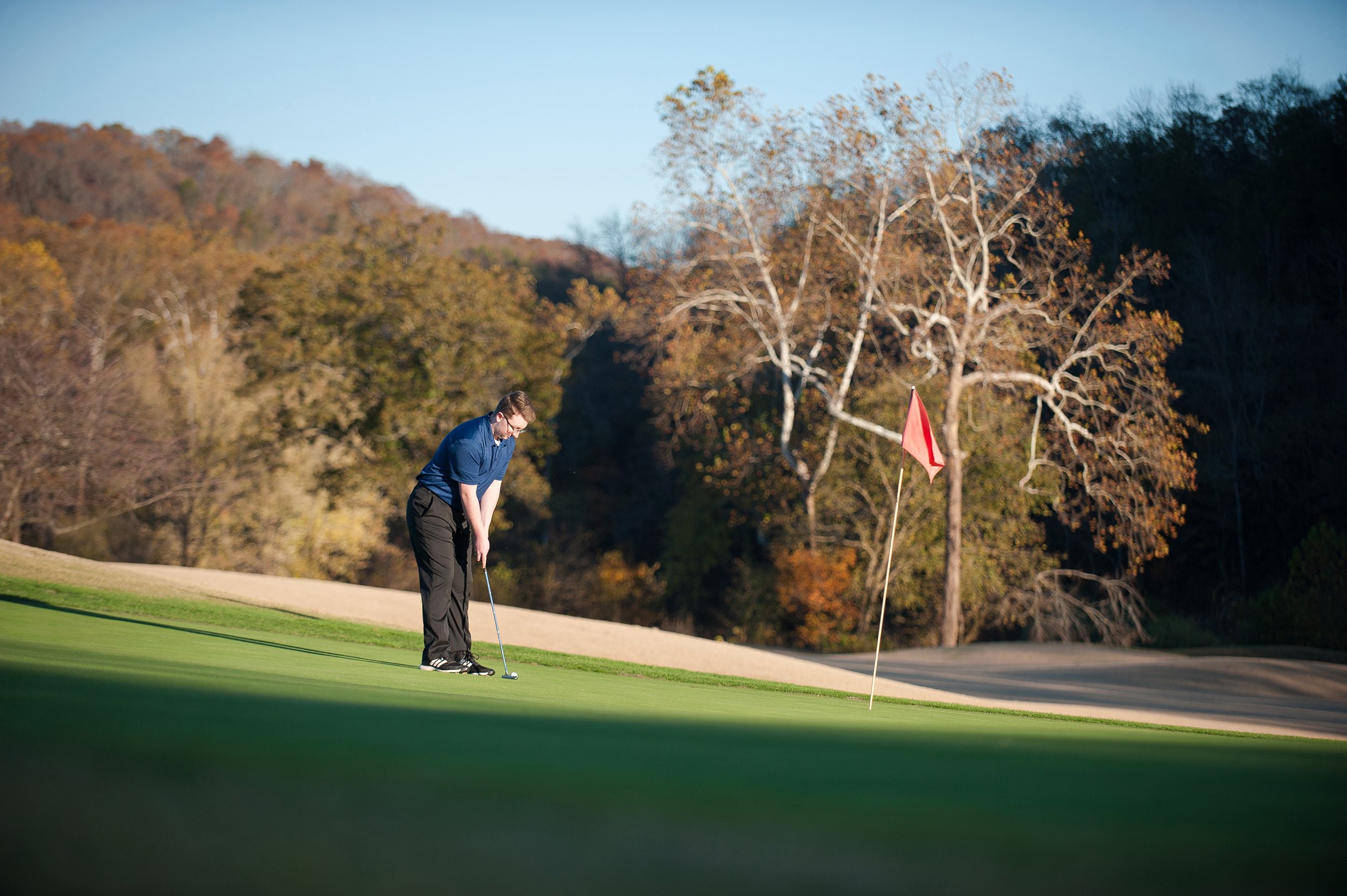 Senior guy in blue shirt putting on green of Indian Tree Golf Course.