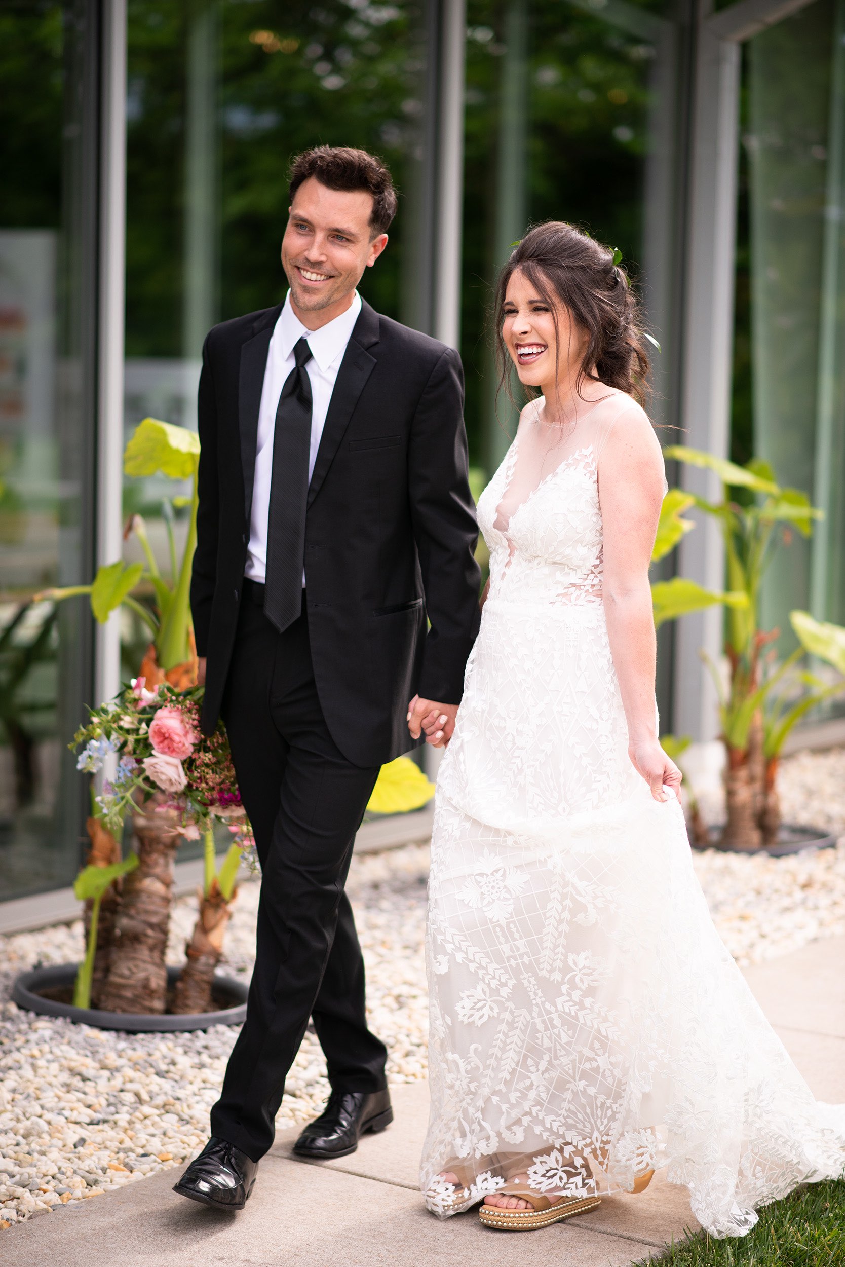 Bride and groom with brown hair walking together near Greenhouse Two Rivers venue.