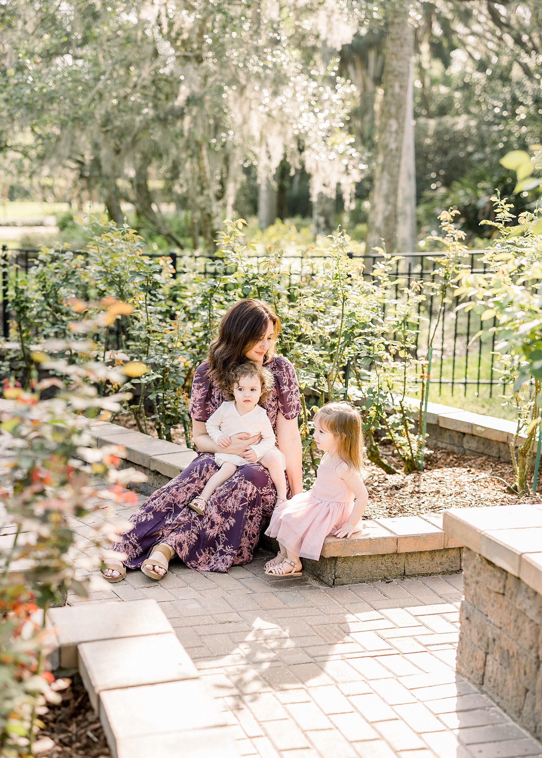 woman in purple dress sitting at Washington Oaks Gardens with children in the spring