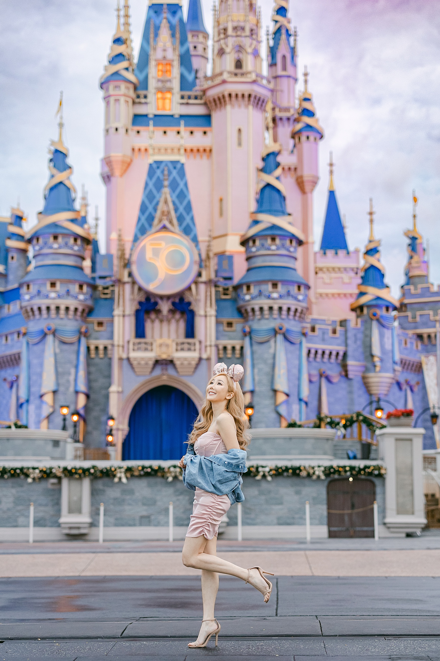 asian influencer milly yang standing in front of cinderella's castle at walt disney world magic kingdom