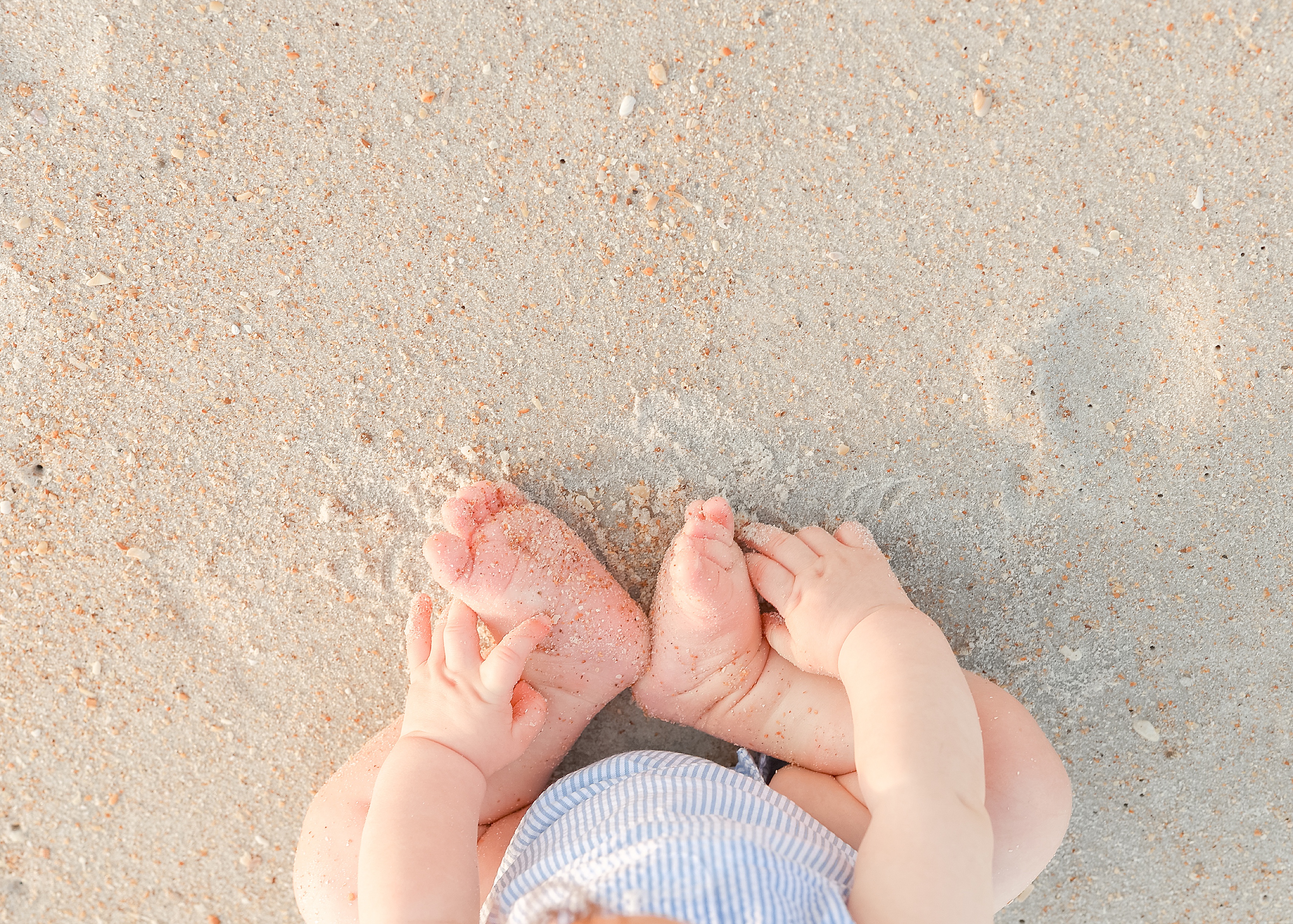 baby boy with sandy feet and toes on the beach at sunrise