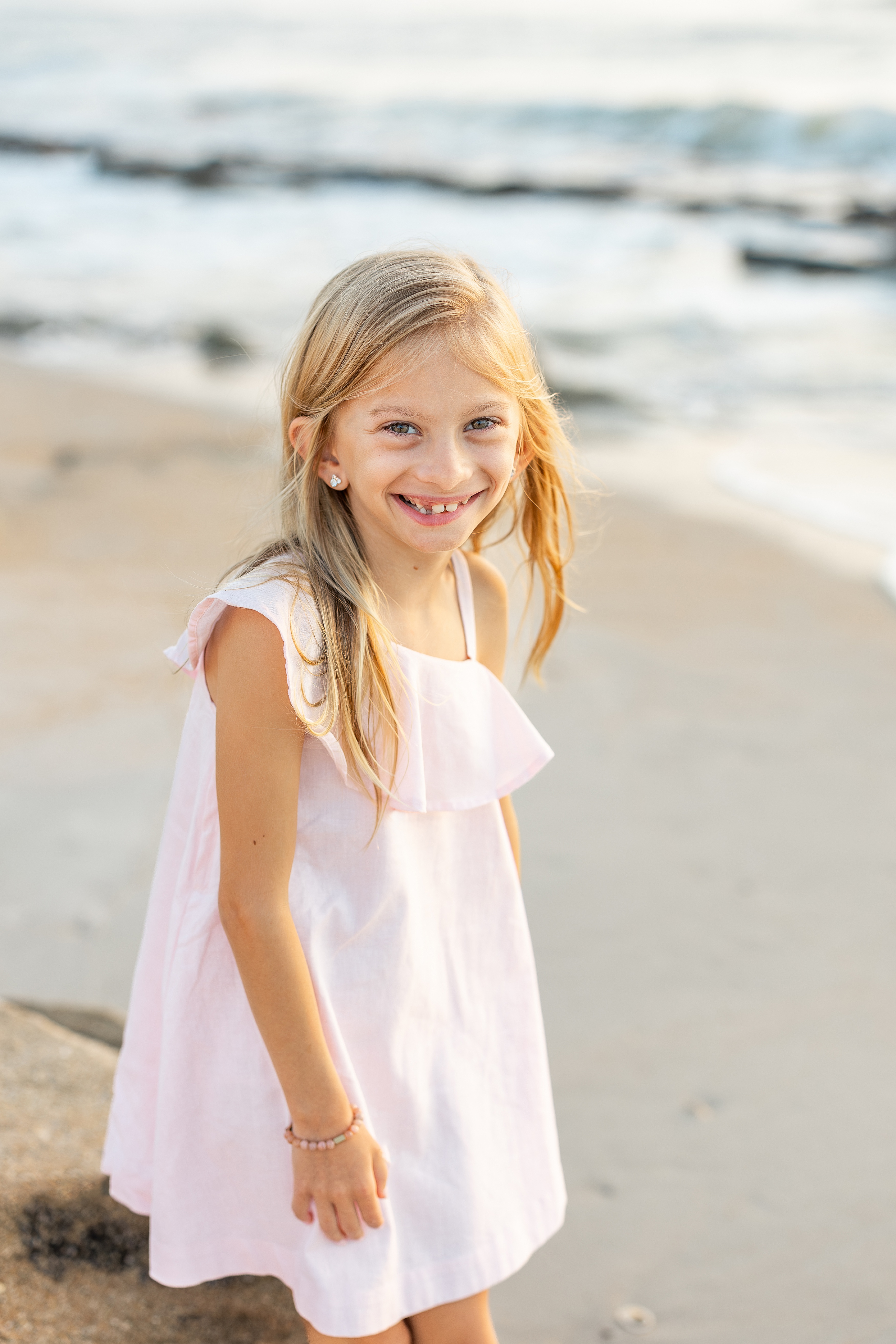 beach portrait of little girl in pink dress at sunrise