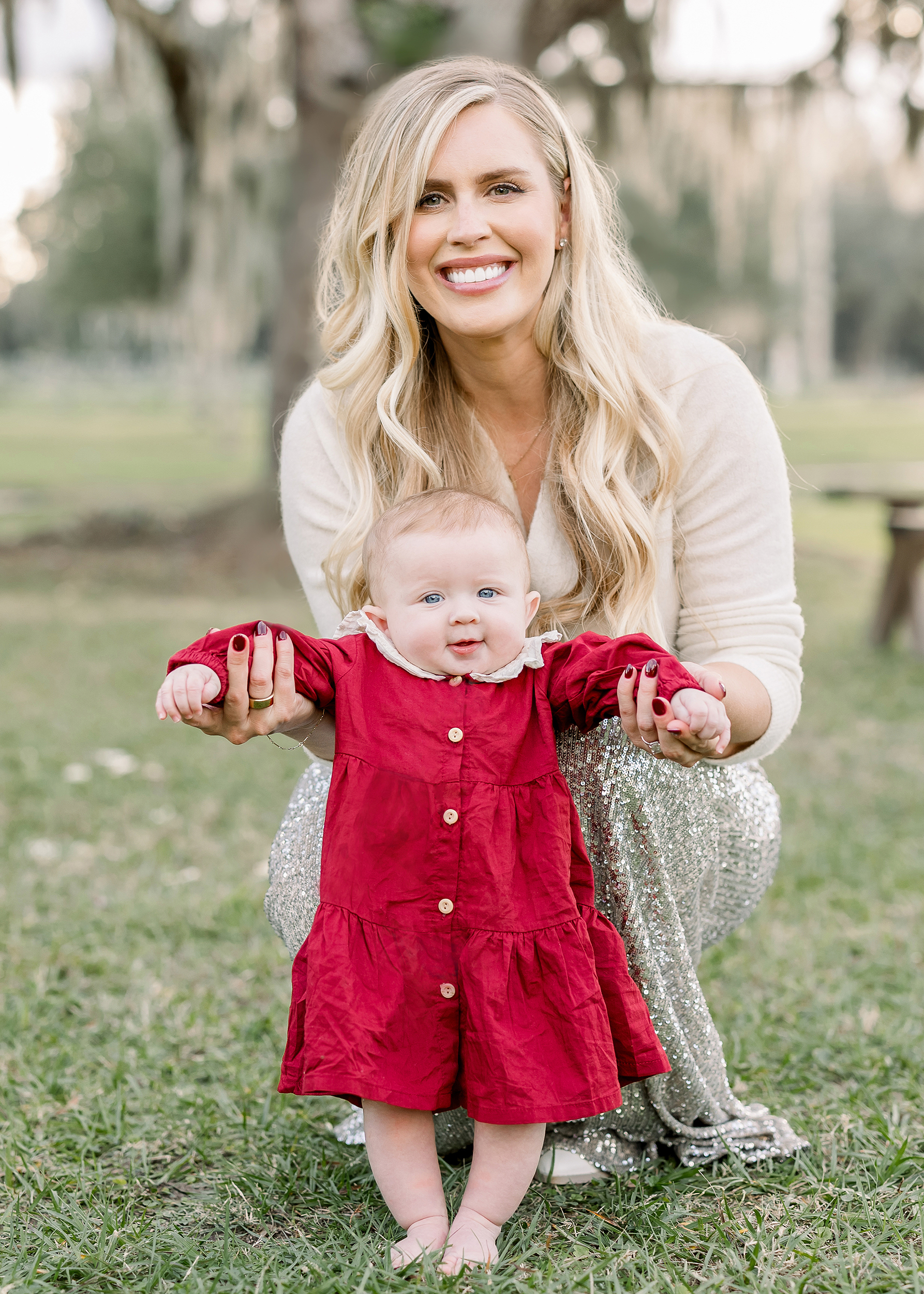 Fall portrait of Kayla Lochte in a silver sequin skit and a cream sweater holding baby girl in a cranberry red velvet dress.