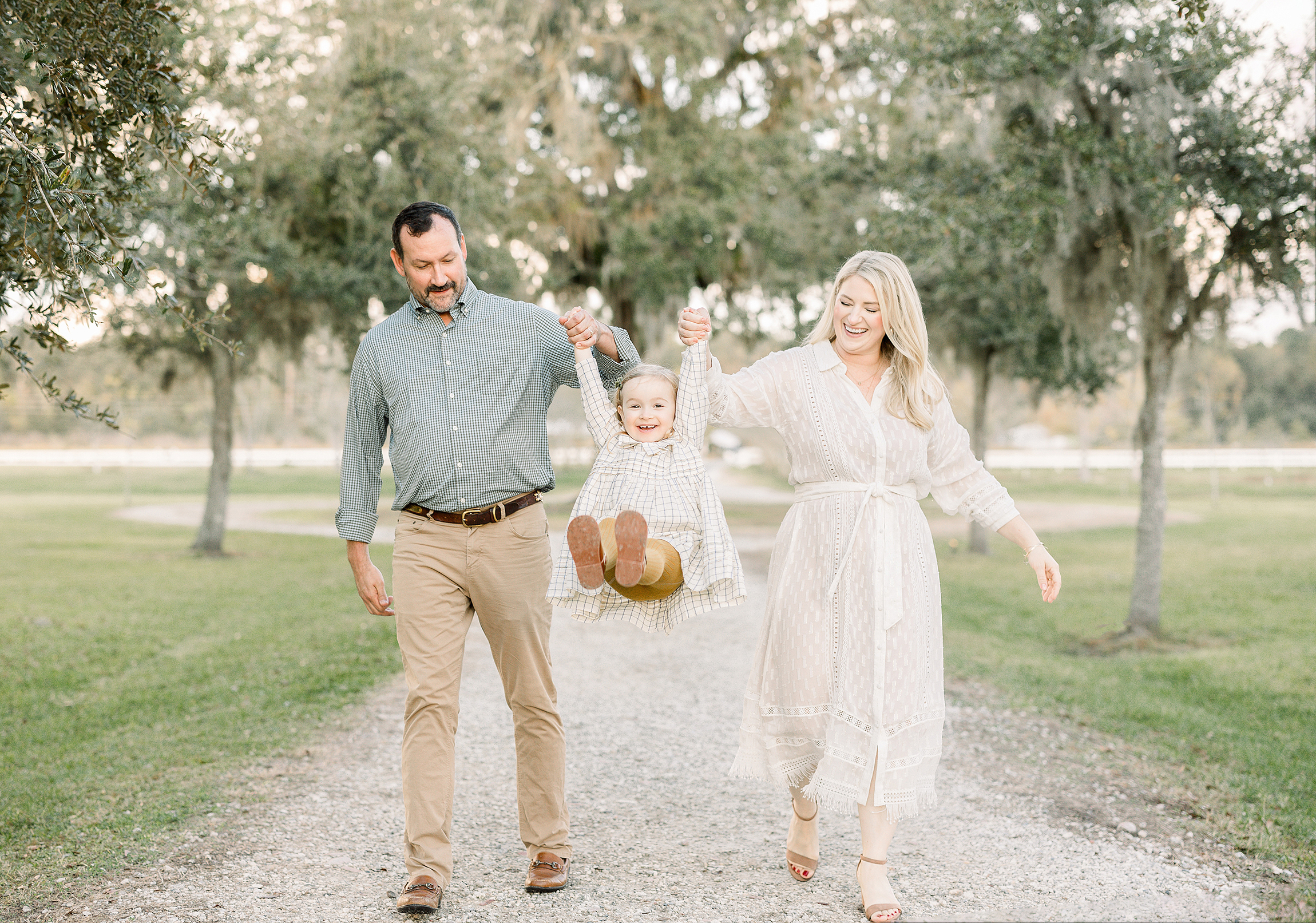 A family dressed for fall swings their little girl on the ground at Congaree and Penn Farm in Jacksonville.