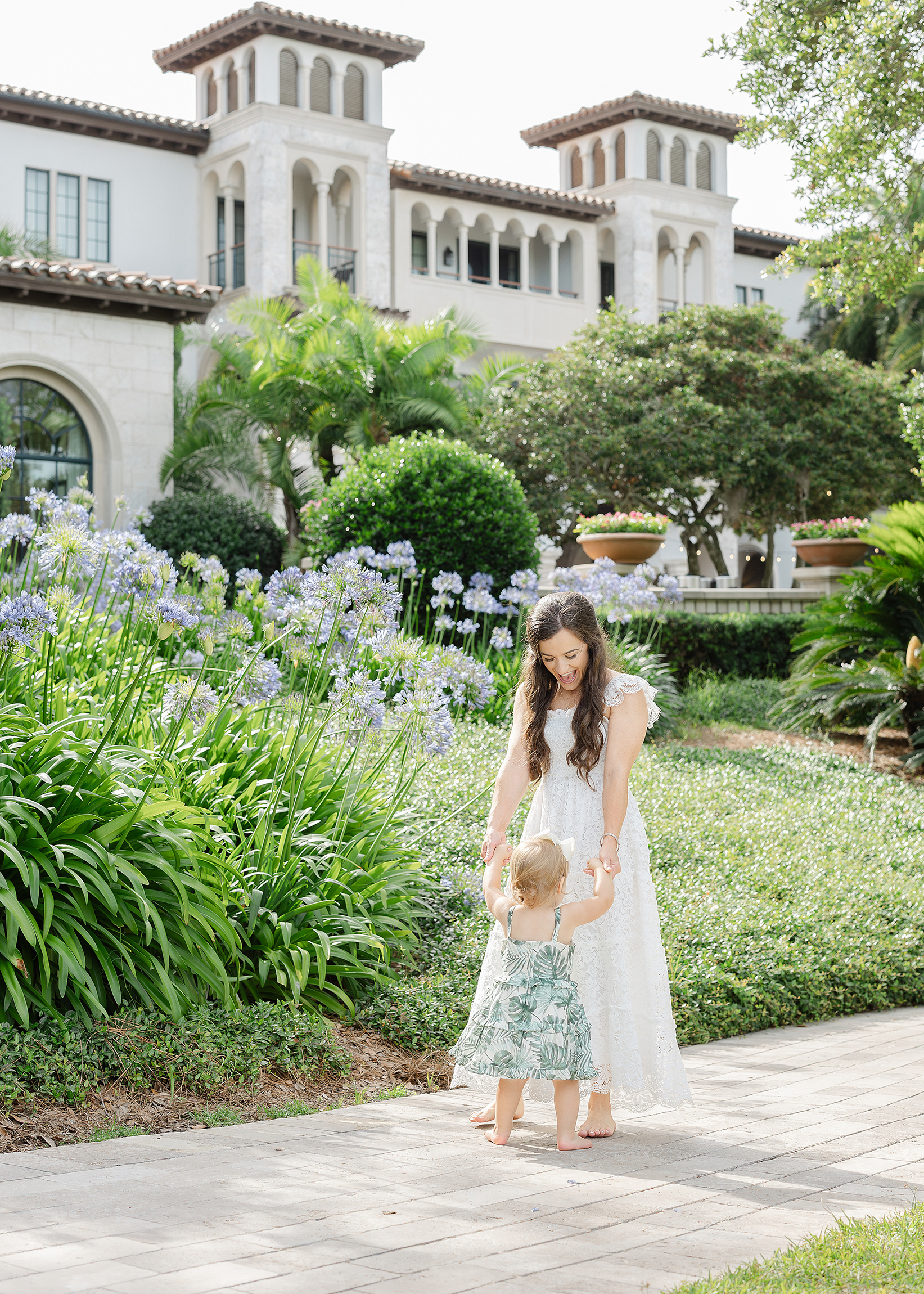 A mother in a long white dress dances with her toddler girl on the grounds of The Cloister in Sea Island, Georgia.