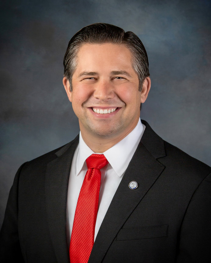 Mayor of Clarksville,Tn in a suit with a red tie against a gray-blue background.