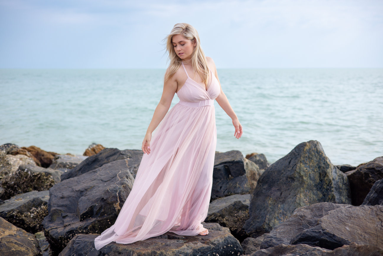 Woman wearing pink dress standing on rocks at Honeymoon Island State Park
