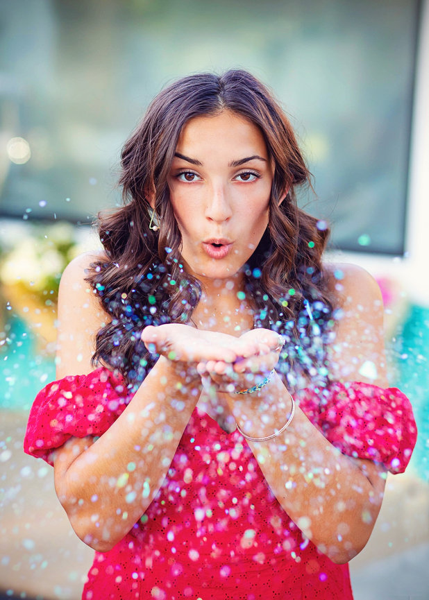 HS Senior girl in red dress in front of aqua wall with confetti