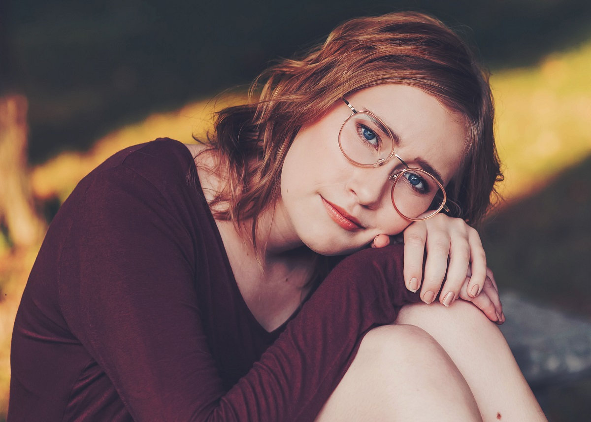 HS senior girl resting head on knees in burgundy. Looks serious