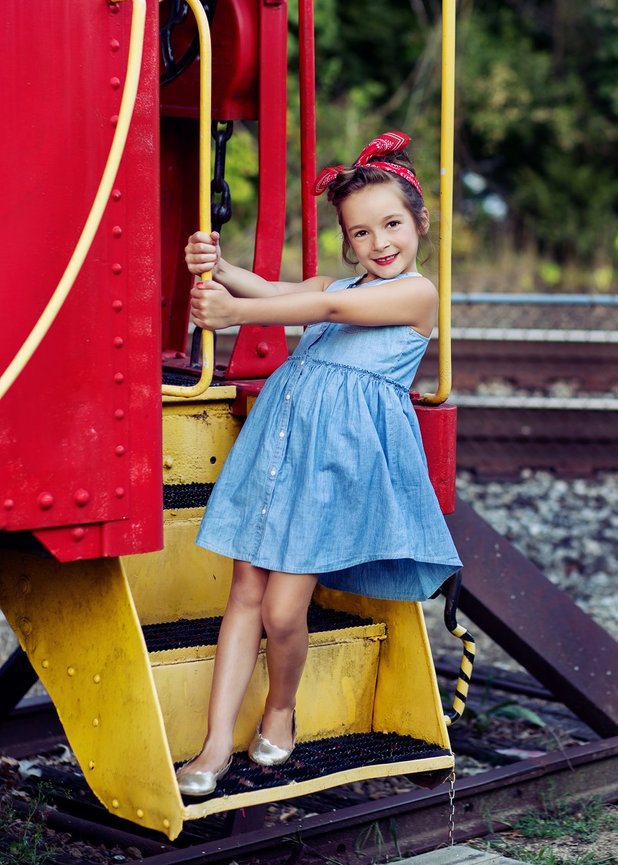 Little girl dressed like Rosie the Riveter on red train caboose