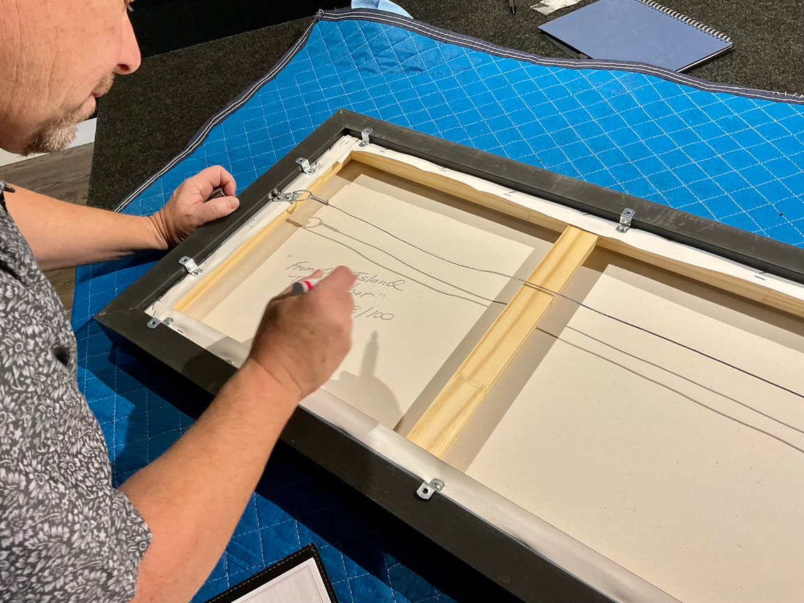 Photographer framing artwork on a studio worktable