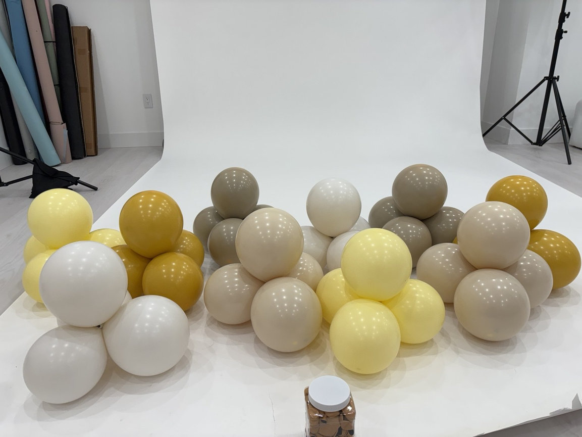 Yellow, cream, and taupe balloon garland being prepared in the photography studio