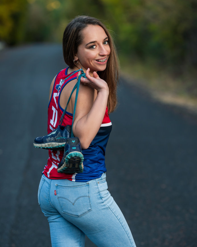 Senior year girl holding track and field shoes and jersey. McCall, Idaho