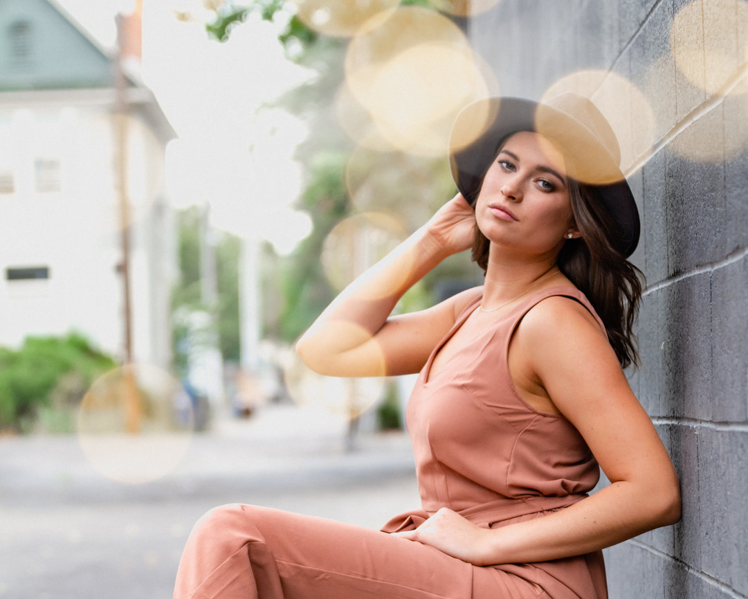 Model styled senior year girl with hat on black brick wall. Boise, Idaho