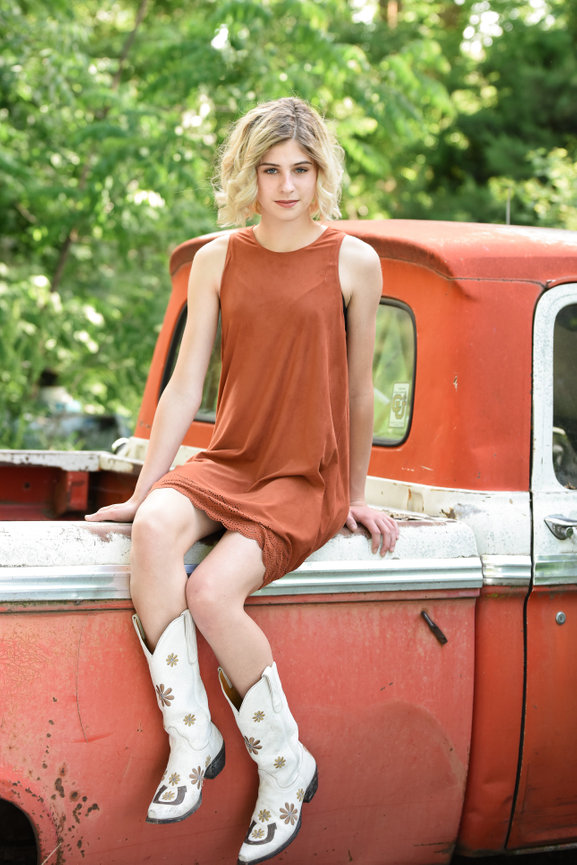 Senior year girl sitting on an old truck in matching boots and dress. Eagle, Idaho