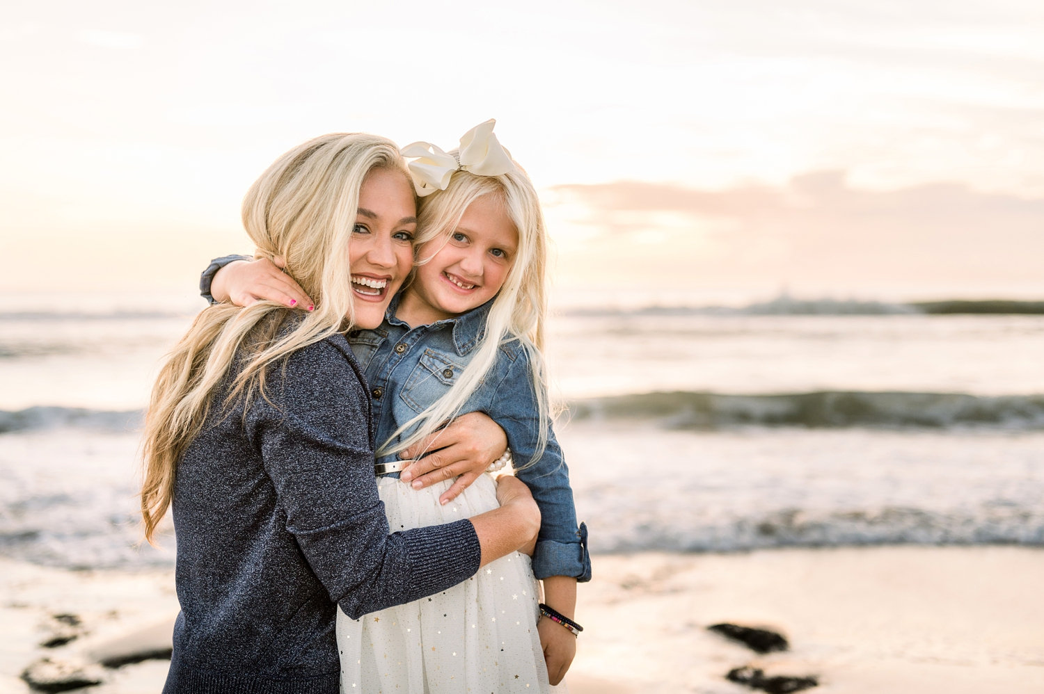 mom and little girl hugging with a Florida beach sunrise in the background