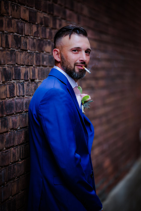 Groom posing against a brick wall